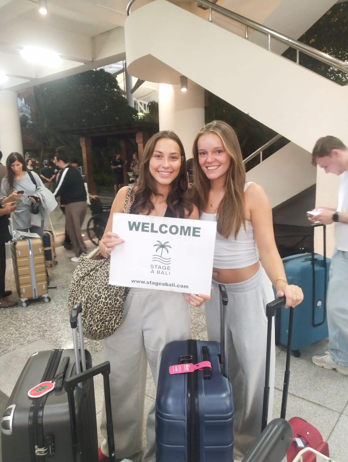 Deux stagiaires Stage à Bali accueillies à l'aéroport avec la pancarte Welcome